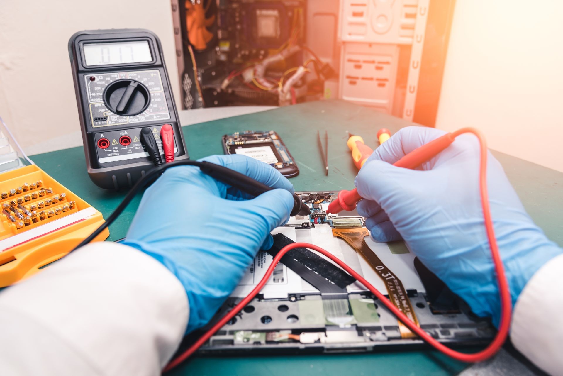 The abstract image of the asian technician repairing a tablet by multimeter in the lab. the concept of computer hardware, mobile phone, electronic, repairing, upgrade and technology.